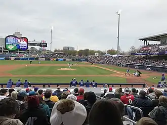 A baseball game being played on a green field involving a team in blue and a team in white