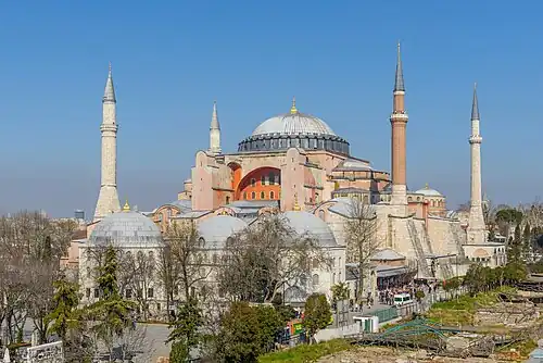 A reddish building topped by a large dome and surrounded by smaller domes and four towers